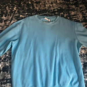 Blå sweatshirt från Weekday - Säljer en stilren blå sweatshirt från Weekday. Tröjan har en klassisk rund halsringning och långa ärmar. Perfekt för en avslappnad look.