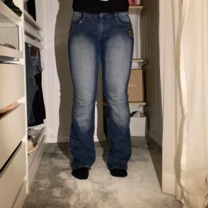 Blå jeans med blommiga detaljer - Snygga blå jeans med bootcut-stil och medelhög midja. De har unika blommiga detaljer vid fickorna både fram- och baktill😻Midjevidd: 42cm. Innerbenslängd: 85cm❣️❣️ Om du har någon fundering är det bara att skriva!