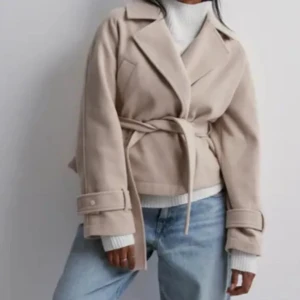 Beige kappa med bälte - Snygg beige kappa med knytbälte i midjan. Jackan har långa ärmar och breda slag, perfekt för en stilren look. Passar bra till både jeans och klänning. Använd men bra skick, skriv för fler bilder och frågor🫶🏼