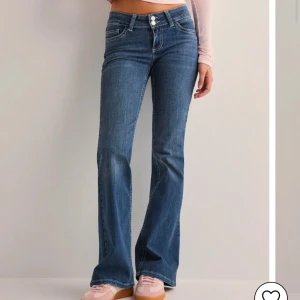 Blå bootcut jeans - Snygga blå bootcut jeans med hög midja och dubbla knappar. De har en klassisk femficksdesign och dekorativa sömmar på bakfickorna. Perfekta för en avslappnad stil. säljer dessa jeans då jag fick dom i julklapp och strl var förstor och prislappen var redan av. aldrig använda. 