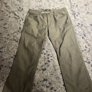 Kostymbyxor  Brothers - Snygga grå byxor från Brothers i en blandning av bomull, nylon och polyester. De har en klassisk design med raka ben och praktiska bakfickor. Perfekta för en stilren look. Sitter rätt slim på mig men har rätt breda lår. 