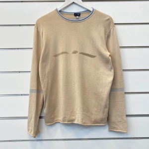 Vintage Armani Jeans Tröja - Tröja ifrån Armani Jean i beige färg med ljusblåa detaljer runtom samt en logga på bröstet. Storlek Large utan defekter.
