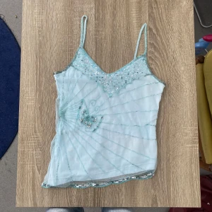 Y2k Linne 2000s Mermaid - Super söt linne i ljusblå färg ifrån märket Tutti Frutti. Massa olika detaljer runtom på plagget, bland annat  en fjäril gjord i paljetter! Storlek medium, mått bifogas nedan.