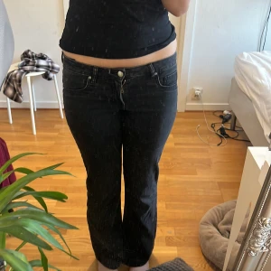 Svarta lågmidjade bootcut jeans - Snygga svarta bootcut jeans med låg midja. Perfekta för en avslappnad stil. Klassisk femficksdesign och knappgylf.