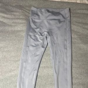 Ljusblå träningsbyxor från Body - Snygga leggings från Body med hög midja och slitsdetaljer vid anklarna. Perfekta för en stilren och bekväm look. Tillverkade i ett mjukt och stretchigt material som ger en skön passform.