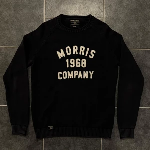 Svart tröja från Morris - Snygg svart tröja från Morris med texten 'Morris 1968 Company' i vitt på framsidan. Tröjan är tillverkad i 100% bomull och har ribbade muddar vid ärmslut och nederkant.