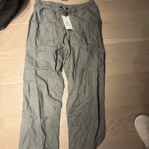 Linnebyxor  - Säljer ett par gröna linnebyxor från Bik Bok i storlek M. Byxorna har en loose passform med elastisk midja för extra komfort. Perfekta för en avslappnad stil.