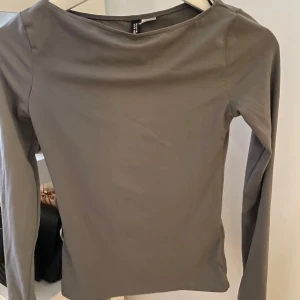 Grå långärmad topp från H&M - Snygg och stilren grå långärmad topp från H&M. Perfekt för lager-på-lager eller som den är. Enkel design med en mjuk och bekväm passform.