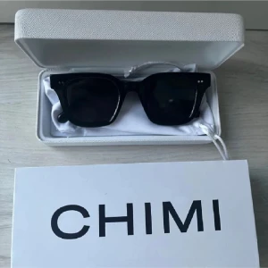 Chimi 04 - Snygga svarta solglasögon från Chimi med en klassisk fyrkantig design. Perfekta för att ge en stilren touch till din outfit. Kommer i ett elegant fodral.