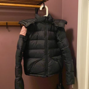 Svart dunjacka från Ralph Lauren - Snygg svart dunjacka från Denim & Supply Ralph Lauren med amerikansk flagga på ärmen. Jackan har en hög krage och dragkedja framtill. Perfekt för kyliga dagar. Jag har använt den men den är fortfarande ett bra skick utom några smink fläckar som knappt syns! Säljer för den är lite för trång❤️