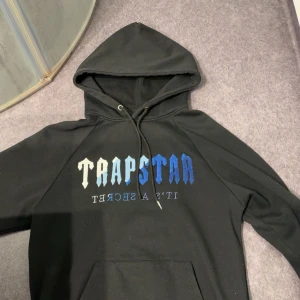 Trapstar hoodie - En svart trapstar hoodie som inte är äkta men som är i storlek S