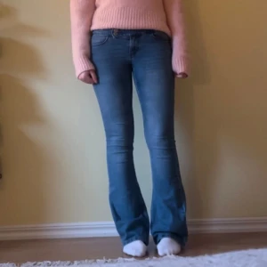 Blå bootcut jeans - Snygga blå bootcut jeans med låg midja och två knappar där fram. Liten deffekt vid fickan på framsidan (se sista bilden) Midja: 36,5cm Innerbenslängd: 79,5cm