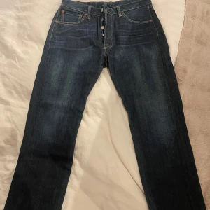 Mörkblå jeans från Levi's - Snygga mörkblå jeans från Levi's med klassisk femficksdesign och knappgylf. Perfekta för en avslappnad stil. De har en rak passform och är tillverkade i slitstarkt denim. Storlek 34/32 men skulle säga att de sitter mer som W33/32 o L31!