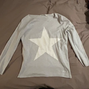 Grå tröja med stjärna från Bondelid - Säljer en stilren grå tröja från Bondelid med en stor vit stjärna på framsidan. Tröjan har långa ärmar och en bekväm passform. Perfekt för en avslappnad stil. Passar xs/s🥰