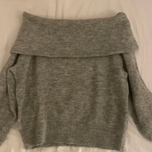 Grå offshoulder tröja från H&M - Mysig grå offshoulder tröja från H&M i stickat material. Perfekt för kyliga dagar med sin ribbade design och långa ärmar. En stilren och bekväm tröja som passar till många tillfällen.💓