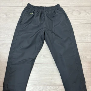 Lacoste Träningsbyxor -  Säljer ett par gråa Lacostebyxor i fleece material. Aldrig använda och skulle säga att de är i storlek M men passar även S. Pris kan disskuteras.