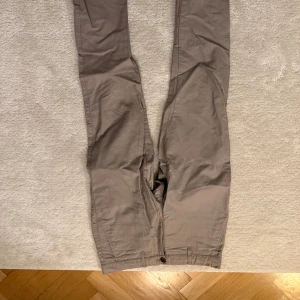 Beige chinos från East west - Snygga beige chinos med slim passform. Byxorna har en klassisk design med knappar och dragkedja framtill. Perfekta för en stilren look. Storlek 30/32. Mycket bra skick. Orginalpris 800 kr.