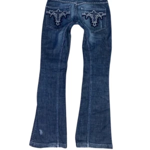 Blå 2000s lågmidjade bootcut jeans från Gina Jeans - Snygga super rare 2000s blå jeans från Gina, med unika broderade mönster på bakfickorna. De är väldigt lågmidjade och bootcut, men alldeles för långa och passade inte mig tyvärr, annars såå snygga! W29 i midjan, men tycker de känns mycket mindre så skulle säga S kanske. Midjemått: 37cm rakt över Innerbenslängd: 86cm  Superfint skick 💗