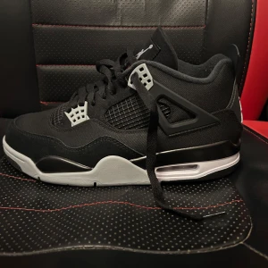 Jordan 4 black canva  - Snygga svarta Nike Air Jordans med grå och vita detaljer. Skorna har en klassisk design med snörning och den ikoniska Jumpman-loggan på hälen. Perfekta för dig som vill ha stil och komfort i ett. Helt nya aldrig använda storlek 42.5