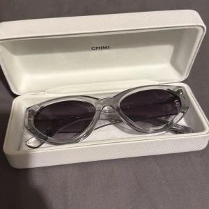 Transparenta solglasögon från Chimi. Modell 06 - Snygga transparenta solglasögon från Chimi med mörka linser. De har en modern och stilren design som passar perfekt för soliga dagar. Kommer med ett elegant vitt fodral med Chimi-logga.