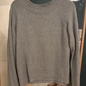 Grå stickad tröja - Säljer en stilren grå stickad tröja med rund hals och långa ärmar. Perfekt för kyliga dagar och enkel att matcha med olika outfits.