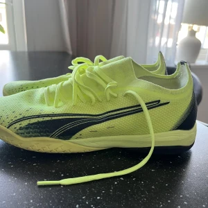 Puma futsal skor - Snygga neongula fotbollsskor från Puma med svarta detaljer och snörning. Perfekta för att sticka ut på planen med sin iögonfallande färg och moderna design.