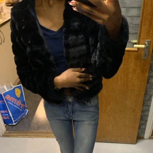 Svart pälsjacka - Snygg svart pälsjacka med långärmad design. Perfekt för att hålla sig varm och stilren under kyliga dagar. Jackan har en mjuk och lyxig känsla.