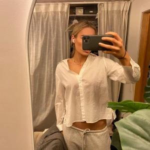 Vit blus med broderade detaljer - Säljer en stilren vit blus med vackra broderade detaljer längs nederkanten. Blusen har långa ärmar och en klassisk krage. Elegant!