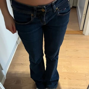 Mörkblå bootcut jeans från Tommy Hilfiger - Snygga mörkblå bootcut jeans från Tommy Hilfiger med låg midja. Klassisk design med fem fickor och knappgylf. Perfekta för en avslappnad stil. (Säljer då de är lite för stora) W26L32