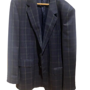 Rutig kavaj från Oscar Jacobson - Snygg rutig kavaj från Oscar Jacobson i mörkblått med diskreta rutor. Perfekt för en stilren look. Kavajen har klassiska slag och fickor framtill.