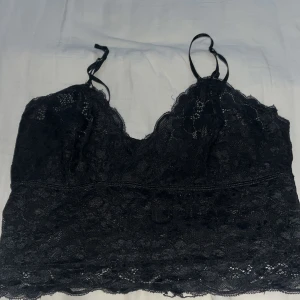 Svart spetslinne - Snyggt svart spetslinne med justerbara axelband och vacker spetsdetalj. Perfekt för en elegant look.