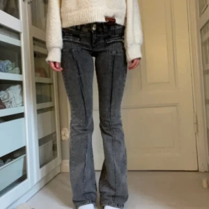 Grå bootcut jeans  - Säljer dessa super snygga grå/svarta bootcut jeans från Nelly. Superfina fickor och knappdetaljer fram på byxorna. (lite slitna nedtill då de är långa, se sista bilden) Skriv vid minsta fundering😊
