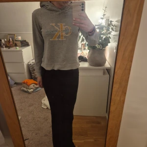 Grå hoodie från Calvin Klein Jeans - Säljer en snygg grå hoodie från Calvin Klein Jeans med deras ikoniska logga i gult och vitt på bröstet. Tröjan har en bekväm passform med långa ärmar och en praktisk huva. Perfekt för en avslappnad stil!