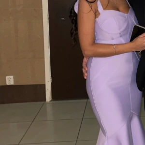 Ljuslila klänning med volang - Elegant ljuslila kjol med volangdetalj i nederkant. Kjolen har en figurnära passform som framhäver silhuetten. Perfekt för en stilren look.