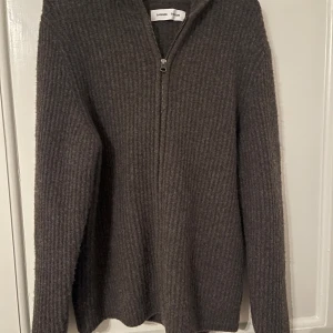Grå ribbad hoodie från Samsøe Samsøe - Säljer en stilren grå ribbad hoodie från Samsøe Samsøe. Tröjan har en dragkedja framtill och en bekväm huva. Perfekt för kyliga dagar. Nästintill oanvänd. Nypris 2999