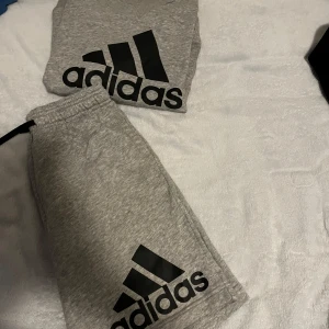 Grå shorts och tjocktröja från Adidas - Snygga grå shorts från Adidas med deras ikoniska logga i svart. Även tjocktröja också. Riktig fresh sommar dress.