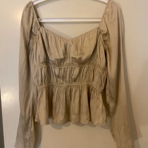 Guldig silkeströja  - Säljer denna fina tröja ifrån h&m i silkes material, fina volanger och detaljer. Använd 2-3 gånger 