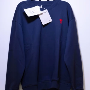 Ami Paris sweatshirt - Helt ny Ami Paris Sweatshirt med ett märke på bröstet. Tröjan har långa ärmar och en klassisk passform. Perfekt för en stilren look. Finns fler storlekar i min profil😁