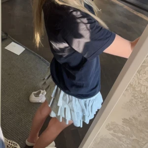 Volangkjol - Söt ljusgrå kortkjol med flera lager av volanger. Perfekt för en somrig look. Kjolen har en elastisk midja för bekväm passform och inner shorts. Storlek xs eller xxs