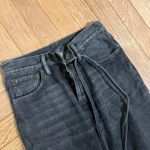 Svarta jeans från Acne Studios - Snygga svarta jeans från Acne Studios med hög midja och knytband i midjan. De har en klassisk femficksdesign och raka ben. Perfekta för en stilren look.