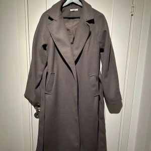 Kappa Gina Tricot - Kappa från Gina Tricot, väldigt fint skick använd endast ett fåtal gånger. Färgen är beige enligt Gina Tricot men skulle säga att den är grå/brun. stl XS