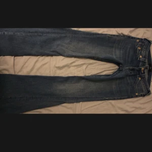 Blå Joey Low Rise Flare Jeans - Snygga blå Joey Low Rise Flare jeans från True Religion. De har en låg midja och en utsvängd stil med dekorativa ficklock bak. Perfekta för en trendig look! Säljer då jag har 2 likadana. Nya med lappar 💗💗