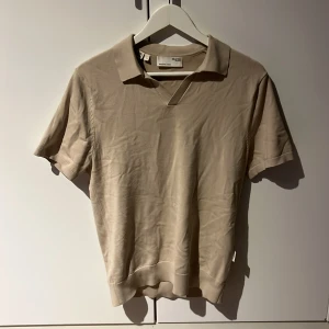 Beige pikétröja från Selected Homme - Snygg beige pikétröja från Selected Homme med klassisk krage och korta ärmar. Finstickad, perfekt till sommaren.                                  Storlek: S                                    Nypris: 500kr