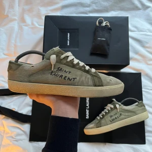 Saint Laurent sneakers - Säljer nu dessa otroligt efterfrågade sl/06 sneakers i den ovanliga färgen oliv. Skorna är använda men har tagits hand om väldigt väl. Stor-papperspåse, extra snören och box medföljer. Allt är såklart og. Dessa går tyvärr inte att köpa nya längre, men nypriset på dessa låg runt 7000kr. Mitt pris är inte hugget i sten, så vid frågor, bud mm är det bara att kontakta mig🤝