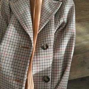 Rutig kavaj från Holly & White - Snygg rutig kavaj från Holly & White i beige, brun och blå toner. Kavajen har en klassisk design med knappar framtill och långa ärmar. Perfekt för en stilren look.