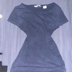 Mörkblå ribbad topp från Levi's - Säljer en mörkblå ribbad topp från Levi's. Den har en tight passform och korta ärmar, perfekt för en stilren look. Materialet är mjukt och stretchigt, vilket gör den bekväm att bära.