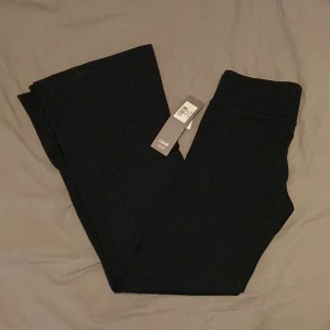 Svarta träningsbyxor - Oanvända endast provade med etiketten kvar från Casall i träningstyg i syntet. Bred linning i midjan, slitsar längst ner på utsidan ca 20cm. Tyget är tunt men håller ändå ihop formen bra, är snygga som vanliga byxor. Tighta från rumpan till knät och sedan vida. Hellånga ben. Medelhög midja