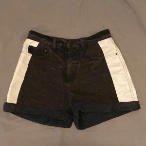 Svarta jeansshorts med vita sidor - Från Monki. Svarta men lite fejksliten färg så typ mörkgrå/svarta. Vita breda streck på sidorna och uppvikta benslut. Medel till höga i midjan beroende på hur man vill att de ska sitta