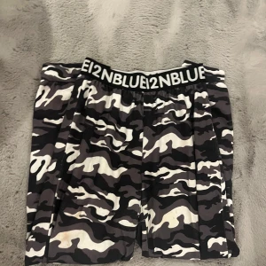 Camouflage byxor från 12NBlue - Snygga camouflage byxor från 12NBlue med elastisk midja. Perfekta för en avslappnad stil eller för träning. De har en klassisk svart, vit och grå färgkombination som ger en cool look.