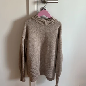 Beige stickad tröja - Säljer en mysig beige stickad tröja med ribbad polokrage och långa ärmar. Perfekt för kyliga dagar med sin mjuka och bekväma passform. Tröjan har ribbade muddar vid ärmslut och nederkant. Slits vid sidorna, längre bak än fram. Passa en xs-s